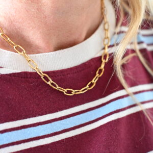 Goudkleurige stainless steel schakelketting met langwerpige schakels gedragen rond de hals